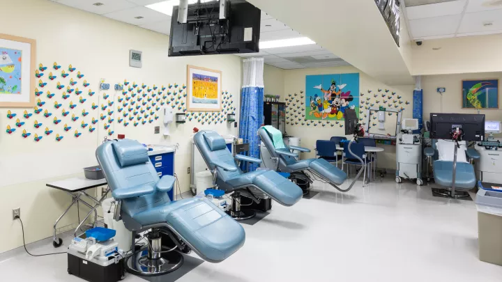 Blue reclining medical chairs surrounded by equipment in a medical office space with colorful art and butterflies on the walls