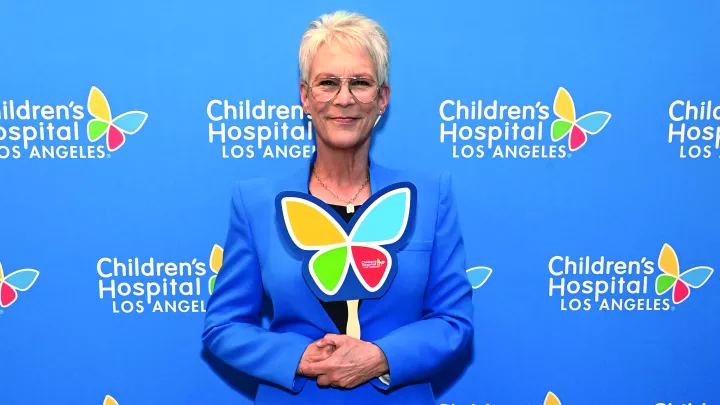 Actress Jamie Lee Curtis, a woman with light skin tone and frosty hair, smiles while holding a CHLA butterfly cutout