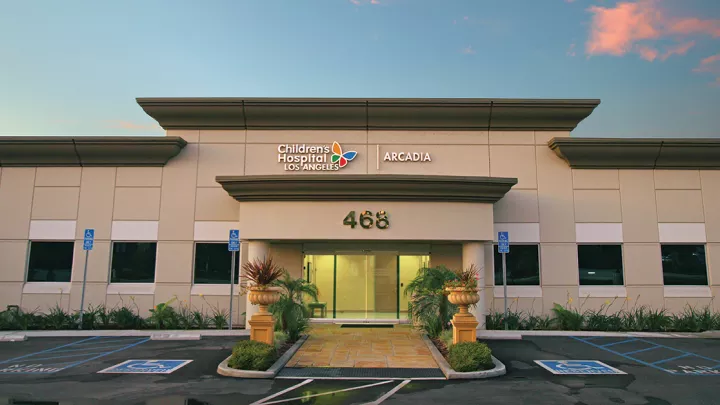 Exterior of entrance to CHLA's Arcadia Specialty Center, a one-story building with the numbers 468 on the facade beneath a blue sky with pink cloud