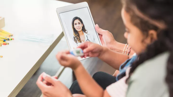 A mother and daughter have a virtual consultation with a doctor