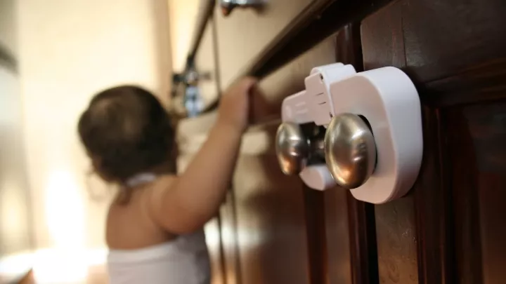 Closeup of a childproof lock on a lower kitchen cabinet.