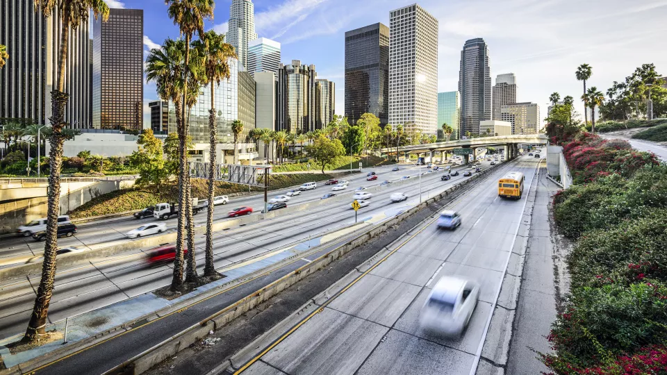 Traffic rushes by downtown Los Angeles skyscrapers