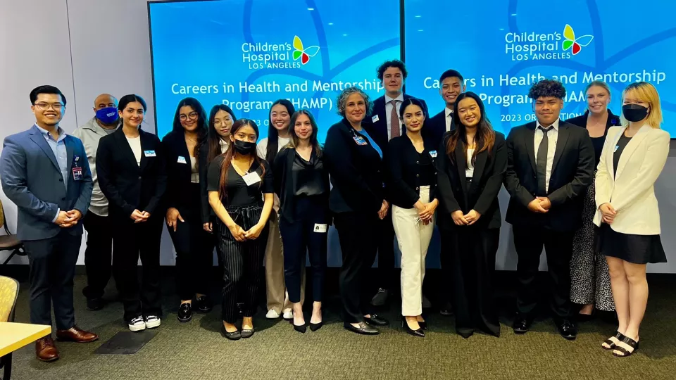 The 2023 cohort of the Careers in Health and Mentorship Program at Children’s Hospital Los Angeles pose in front of oversized digital TV monitors