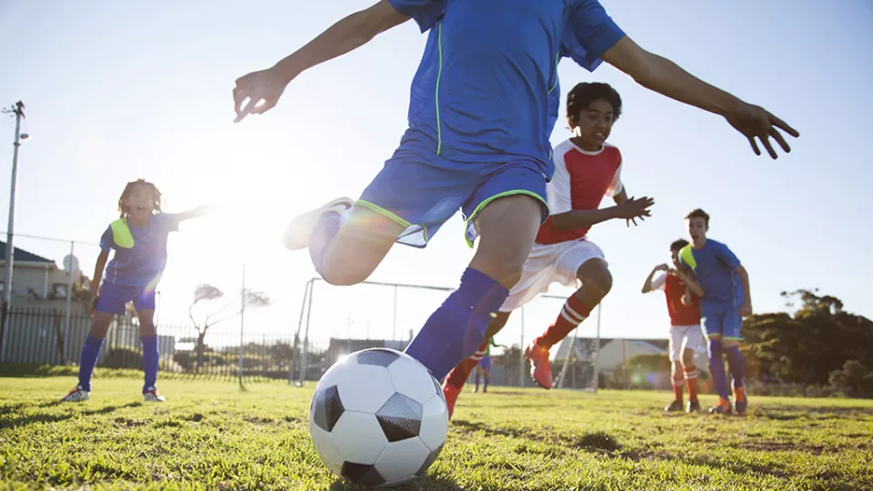 Close up action of boys soccer teams playing a football match