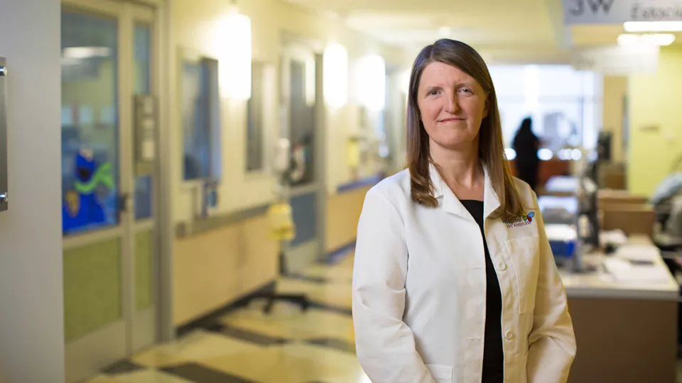 Rachel Chapman, MD, stands in hospital corridor wearing white lab coat