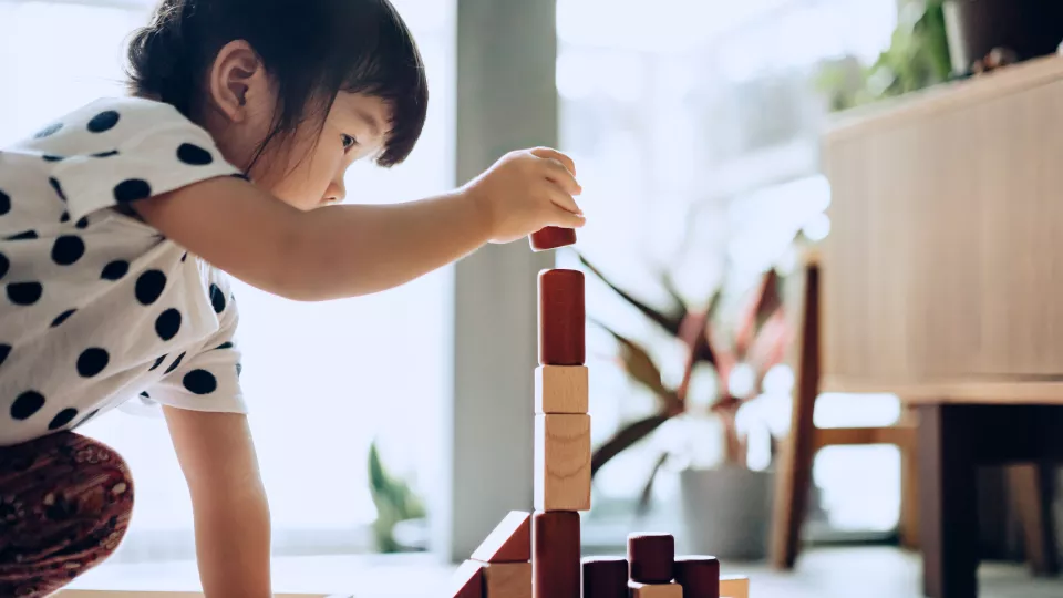 A toddler plays with blocks on the floor.