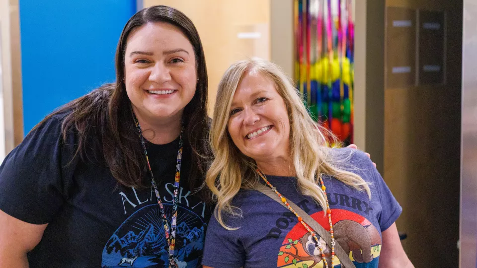 Two nurses smile at the camera.
