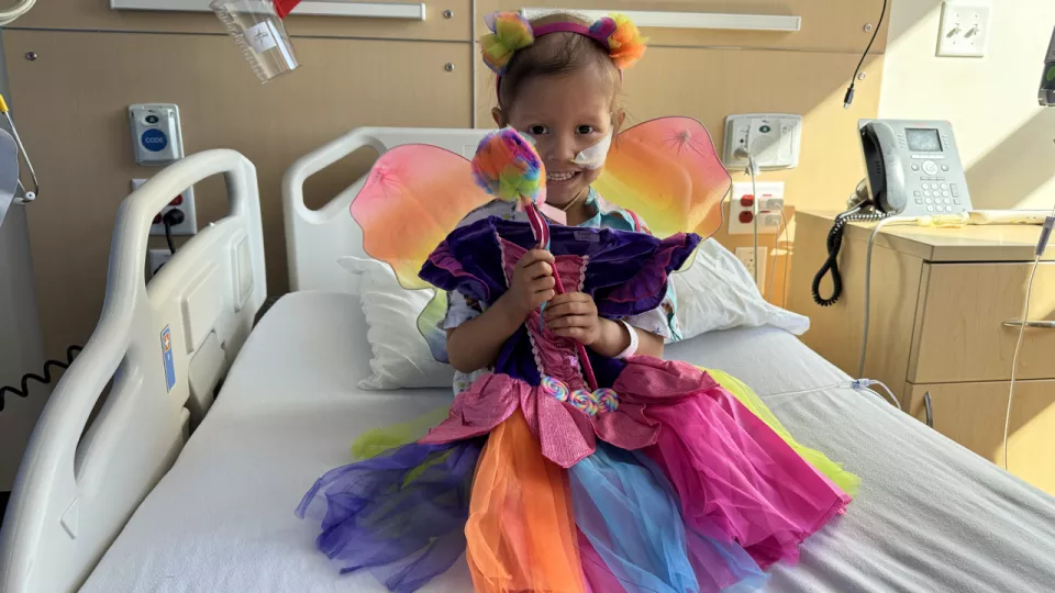 A young patient poses on her hospital bed in the new colorful fairy Halloween costume she just picked out.