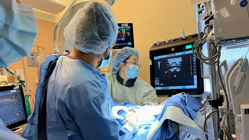 Physicians wearing full personal protective equipment tend to a patient in a hospital operating room