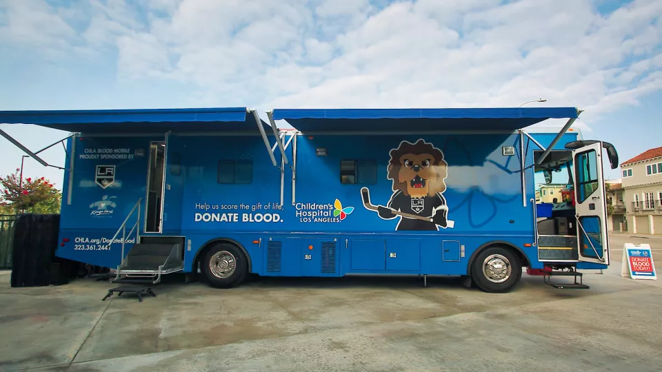 Children's Hospital Los Angeles' bright blue mobile blood donation bus with open doors and extended awnings