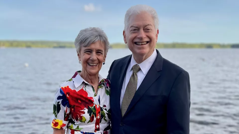 Mindy and Gene Stein smile as they stand on a wooden dock against the background of a waterway
