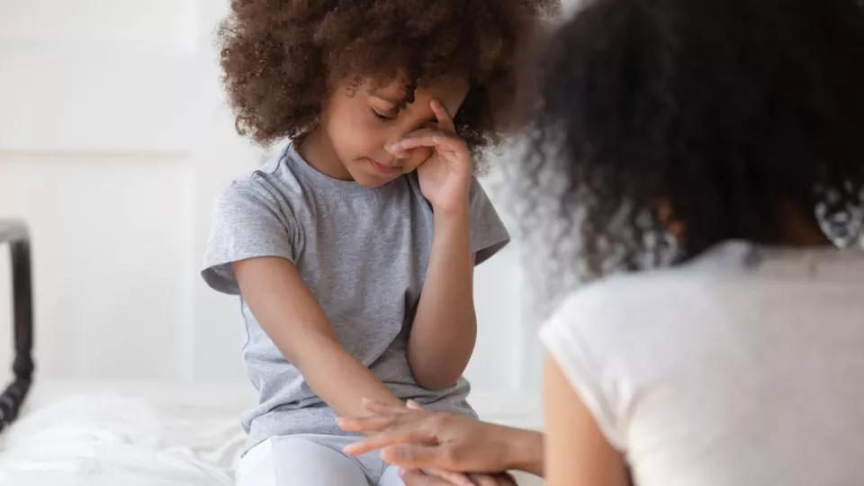 Young African-American girl crying and being comforted by mother