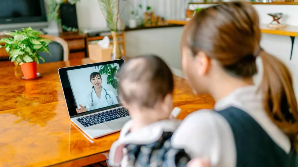 Mother and baby looking at laptop for a virtual appointment with doctor