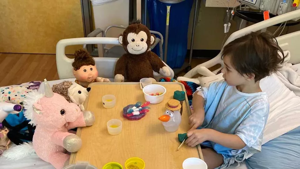 Emme sitting at hospital bed table with her stuffed animal friends