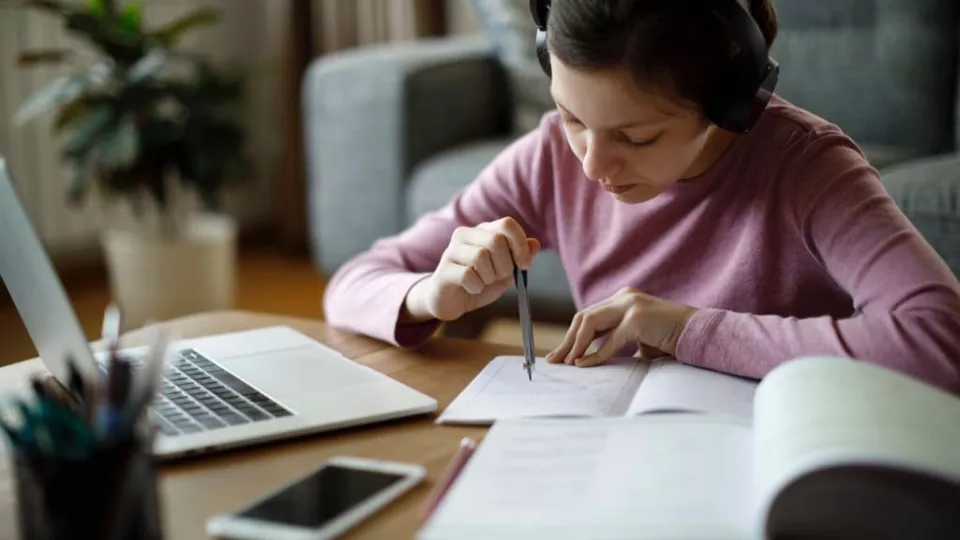Young girl wearing headphones while doing homework