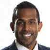 Headshot of man with dark skin tone and dark hair wearing business attire