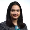 Headshot of woman with medium skin tone and dark hair wearing business attire