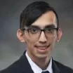 Headshot of man with light skin tone and dark hair wearing glasses and business attire