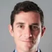 Headshot of a man with light skin tone and dark hair wearing business attire