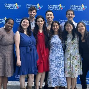 Six young women and three young men stand in two rows against a blue Children's Hospital Los Angeles backdrop