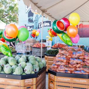 Large crate of watermelons beside large crate of carrots, with balloons tied to crates