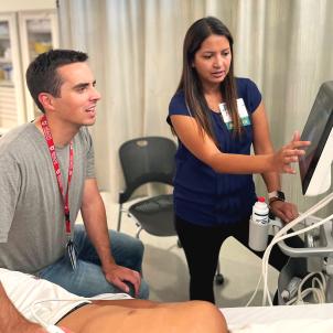 Female physician instructs a male trainee as he uses a sonogram on a medical mannequin