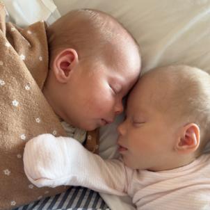 Two light-skinned babies sleeping while touching foreheads