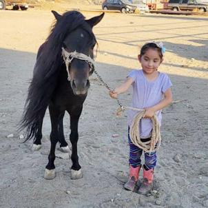 Natalia with a pony on her family's farm, pre-surgery