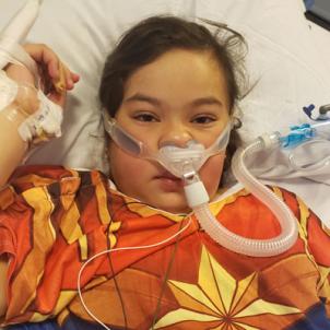 Xitlali laying in a hospital bed with a breathing device strapped to her nose