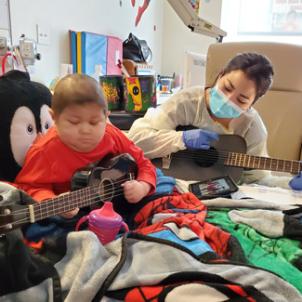 Nano and CHLA music therapist, Hana Cho, play guitars together