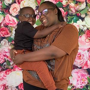 D'Kai's mother Jazmin holds her son in her arms against a backdrop of roses