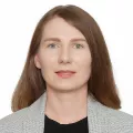 Headshot of a woman with light skin tone and light brown hair wearing business attire against a white background