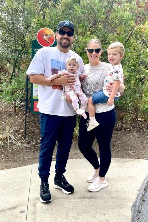 A family of four, adult male holding a female baby and adult female holding a male toddler enjoying the outdoors