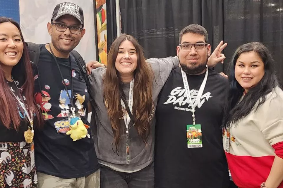 Extra Life team members pose arm-in-arm in front of convention booth