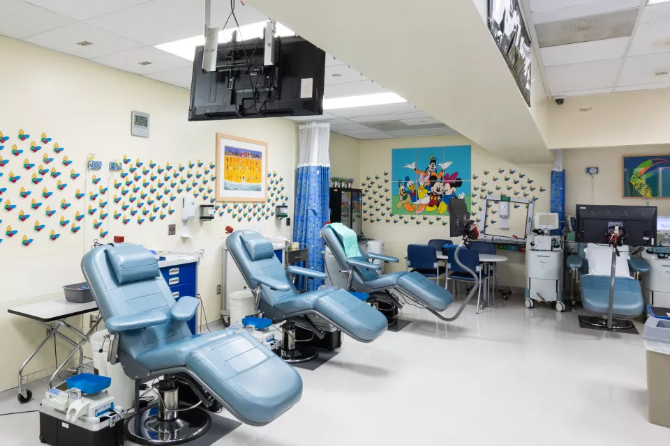 Blue reclining medical chairs surrounded by equipment in a medical office space with colorful art and butterflies on the walls