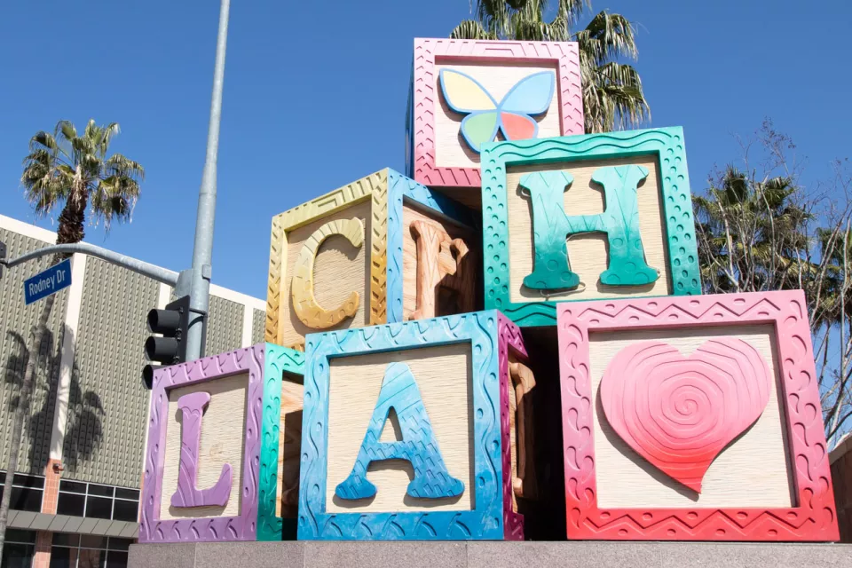 A large, colorful statue of children's toy blocks with the letters C-H-L-A on them, as well as a heart and butterfly logo.
