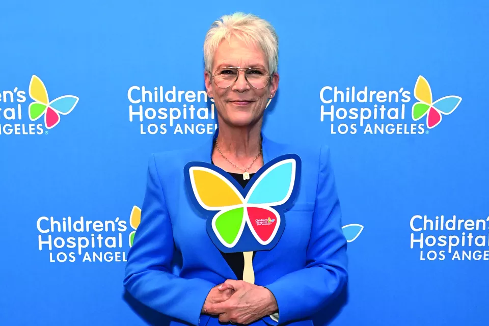 Actress Jamie Lee Curtis, a woman with light skin tone and frosty hair, smiles while holding a CHLA butterfly cutout