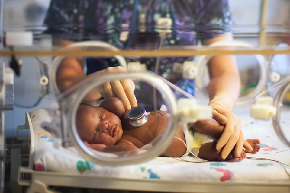 Nurse checking premature baby's heartbeat inside an incubator at CHLA NICCU