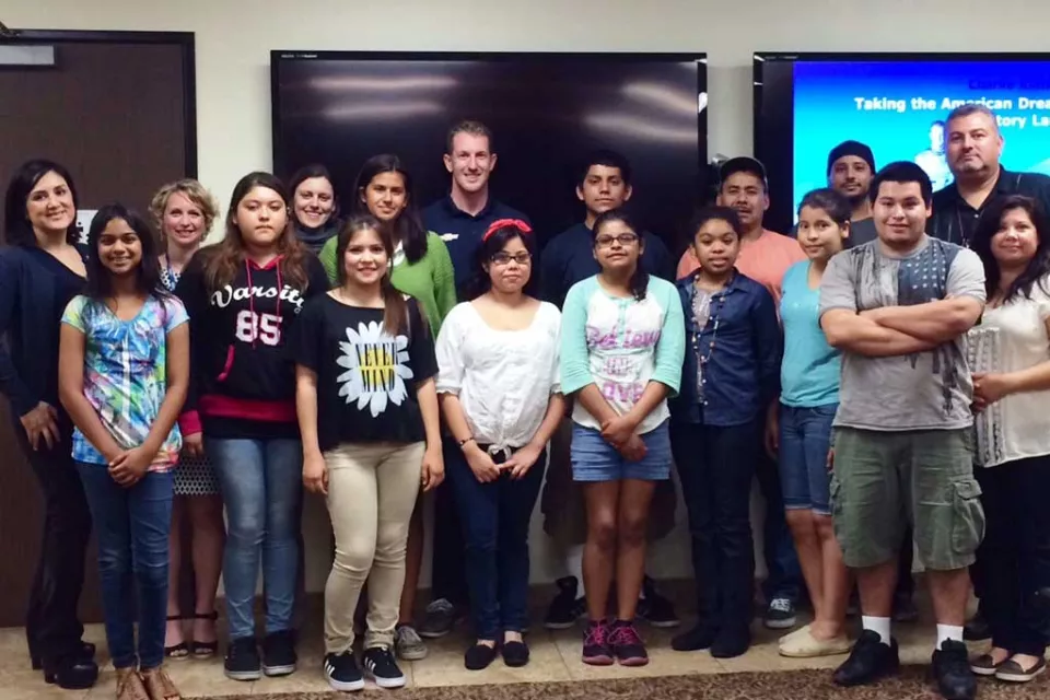 18 teens and adults of varying ethnicities pose and smile.