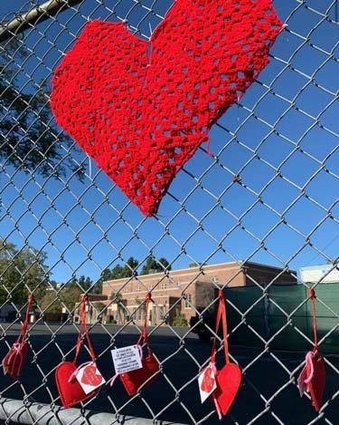 Heart crafts hanging from a chain link fence
