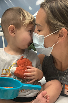 Melinda, wearing a surgical mask, nuzzles with her son Kai