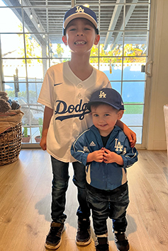 Kai and his big brother Cruz smile and pose for the camera wearing their Los Angeles Dodgers fan gear