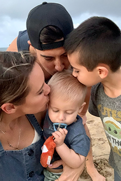 Family photo of mom, dad and brother Cruz kissing Kai