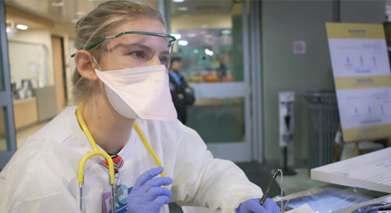 Woman staff member wearing personal protective equipment while at computer - Coronavirus Safety at Children's Hospital Los Angeles