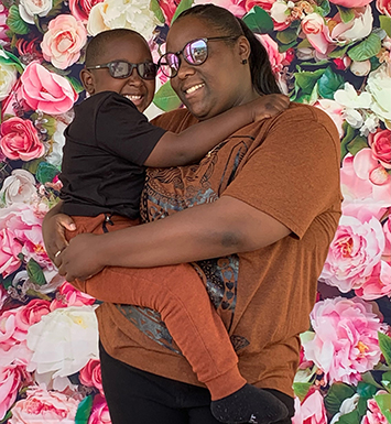 D'Kai's mother Jazmin holds her son in her arms against a backdrop of roses