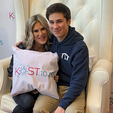 Ellen K and her son, Calvin sit together on a white leather chair