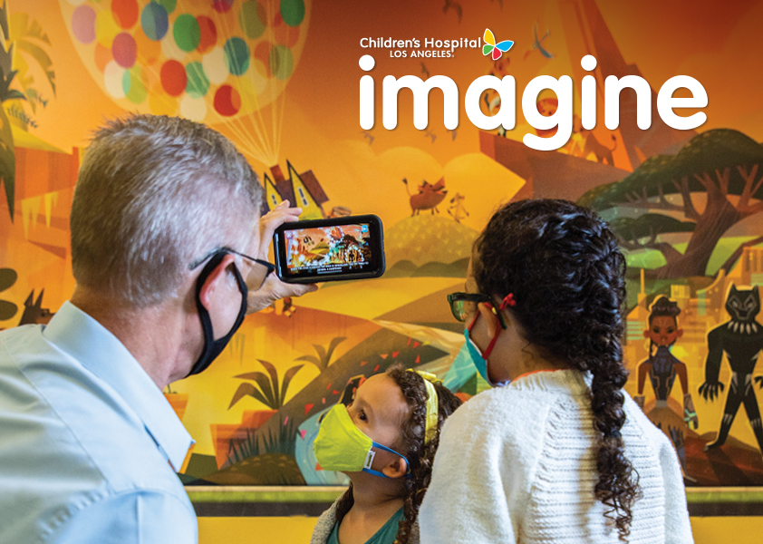 Cover image of Imagine Winter 2020 showing a doctor and children viewing a Disney mural using a phone augmented reality app