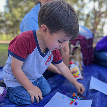 Little boy Martin plays with brightly colored shapes on a blanket outside