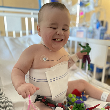 Young Oliver laughs as he plays with toys in his CHLA hospital bed