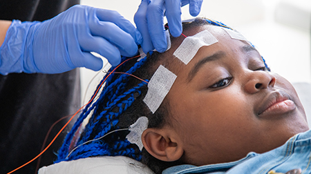 Wires being taped to the head of a relaxed child